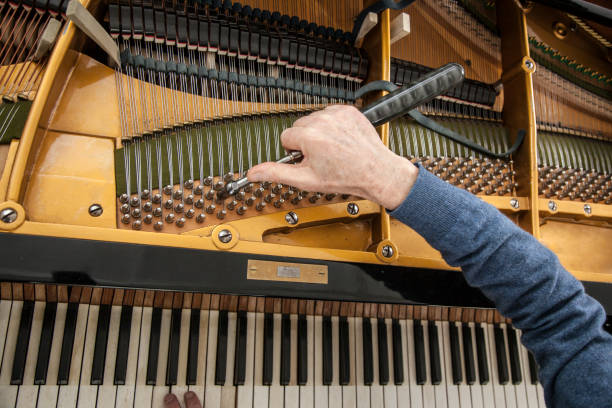 closeup of hand and tools of tuner working on grand piano closeup of hand and tools of tuner working on grand piano